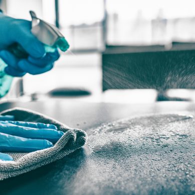 Cleaning home table sanitizing kitchen table surface with disinfectant spray bottle washing surfaces with towel and gloves. COVID-19 prevention sanitizing inside